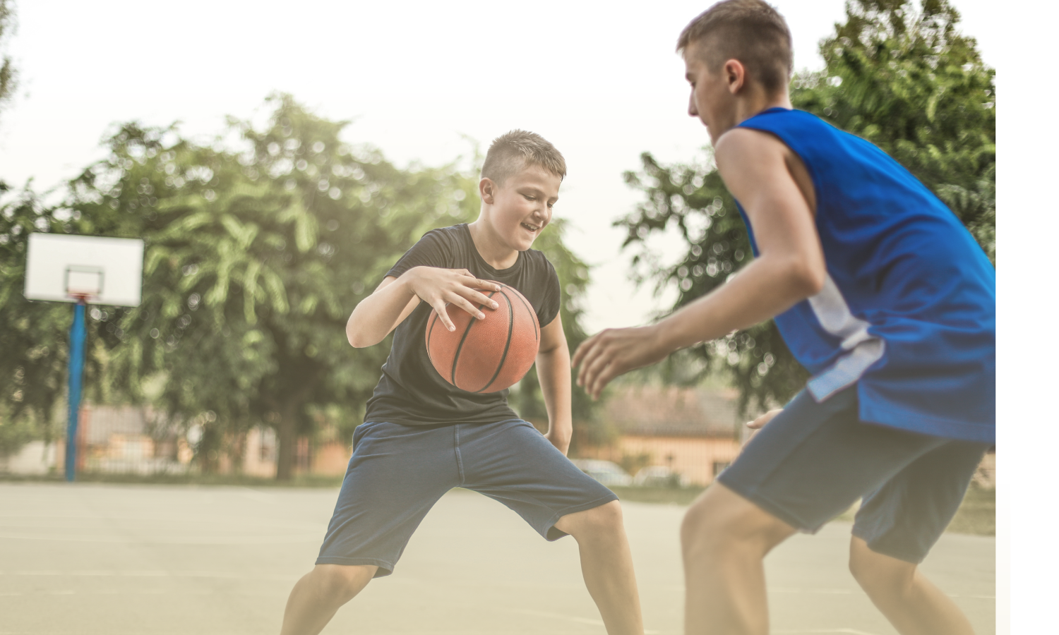 Two teen boys playing basketball outside