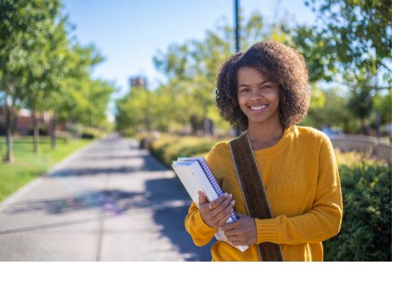 Young woman standing outside on college campus smiling.