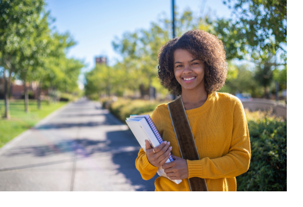 Young woman standing outside on college campus smiling.