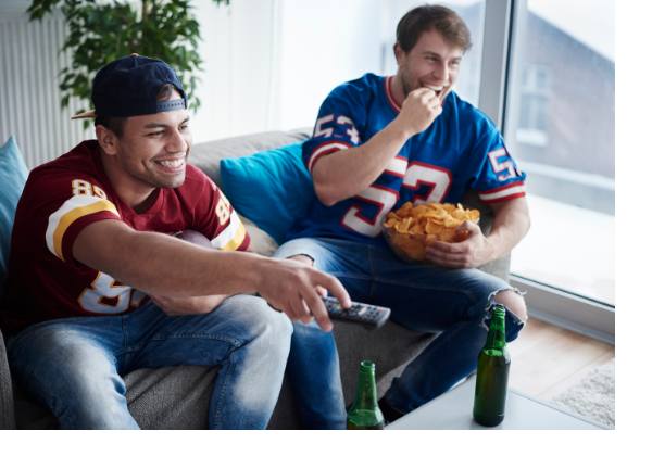 Two young men sitting on couch watching athletic event on tv