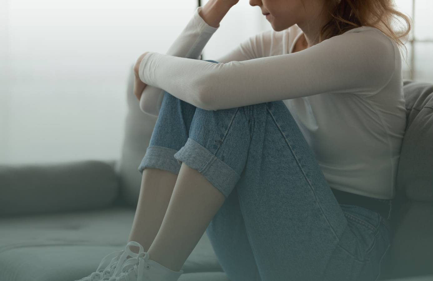 Teen girl sitting on couch, looking concerned.