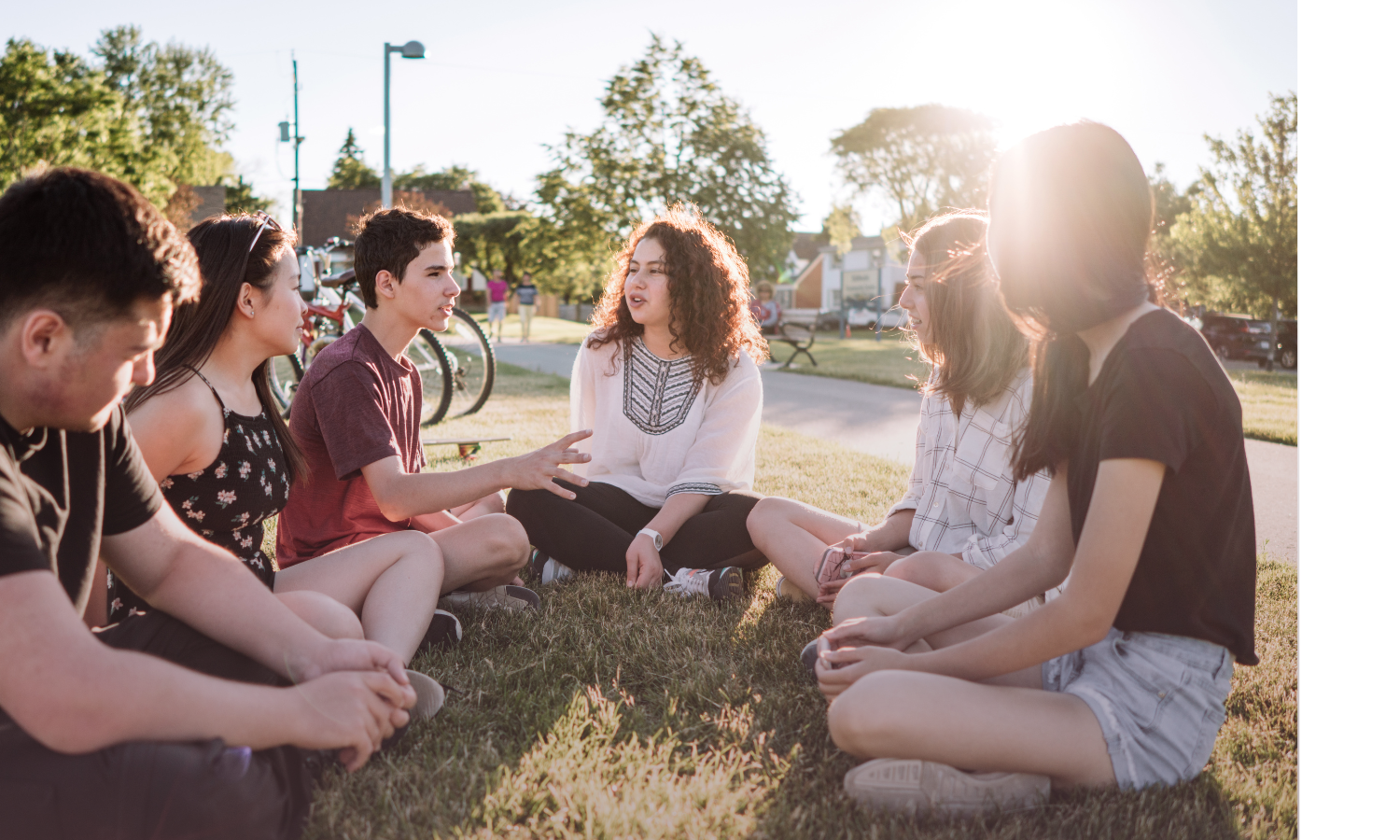 Group of teens sitting in the grass outside a school