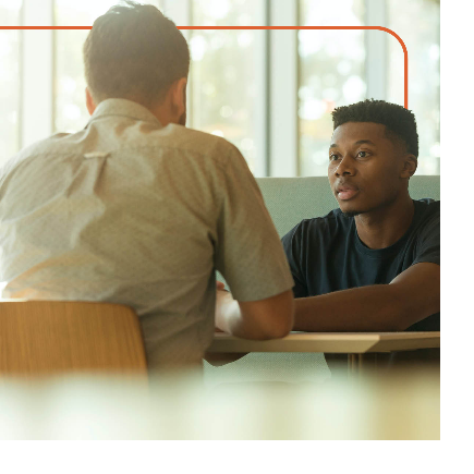 Young man and teen talking at a table.