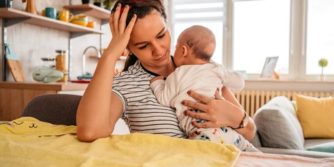 Mother holding her newborn baby feeling sad