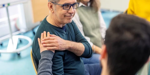 Senior man getting emotional support during group therapy session