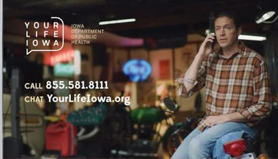 a man on a cell phone, seated in a garage
