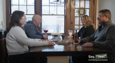 4 adults sitting at a dining table with wine and beer