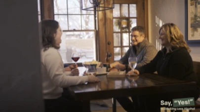 3 people sitting at a dining table with wine