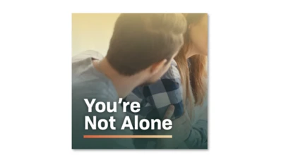 close up of two people sitting together with the text, "You're Not Alone."