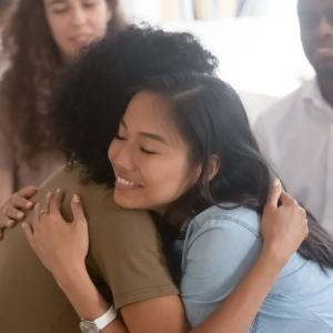 Two women smile and share a hug