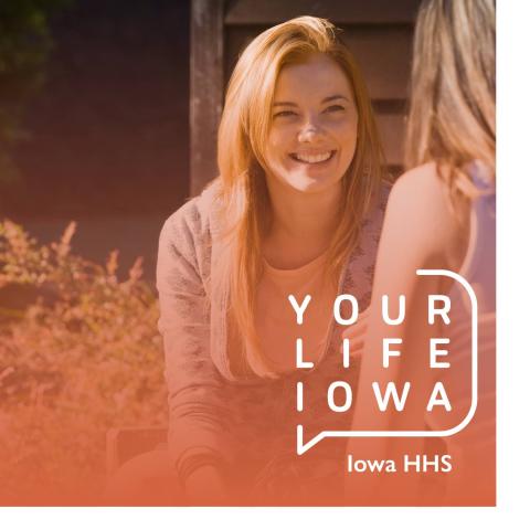 Young woman sitting outside talking to another young woman, smiling