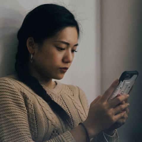 A woman stares at her phone screen