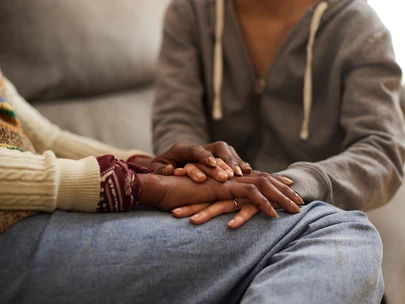 Two people holding hands and comforting one another
